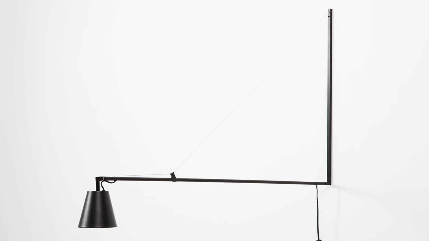 The Petrie contemporary Swing Arm Wall Lamp on a white wall angled down