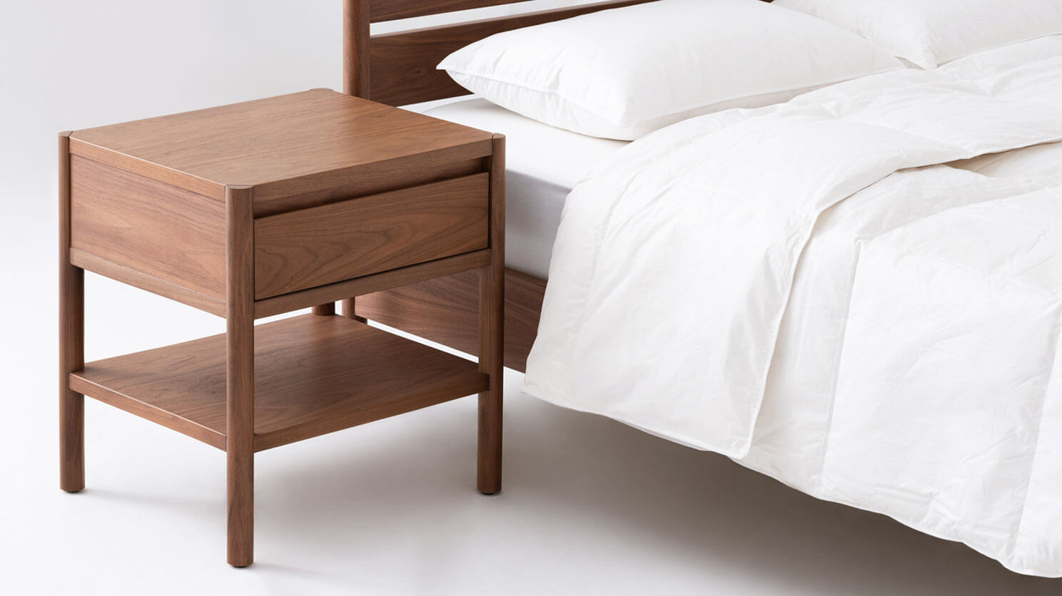 The Monarch single drawer low nightstand in walnut beside its matching bed