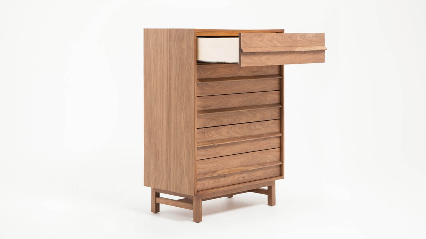 Angled view of the Marcel bedroom chest in walnut with top drawer open