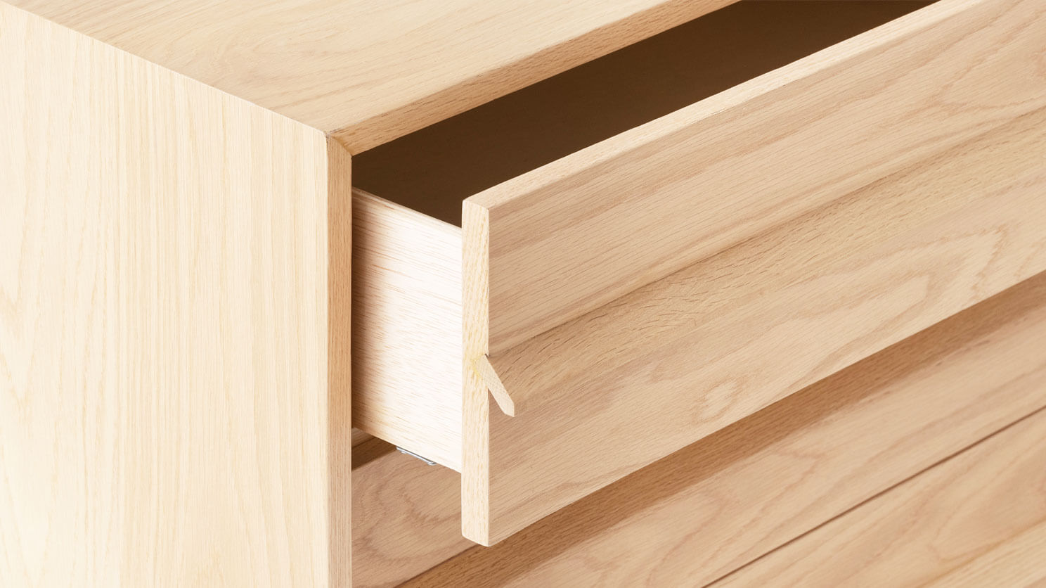 Detail view of the Marcel bedroom dresser in oak with drawer open