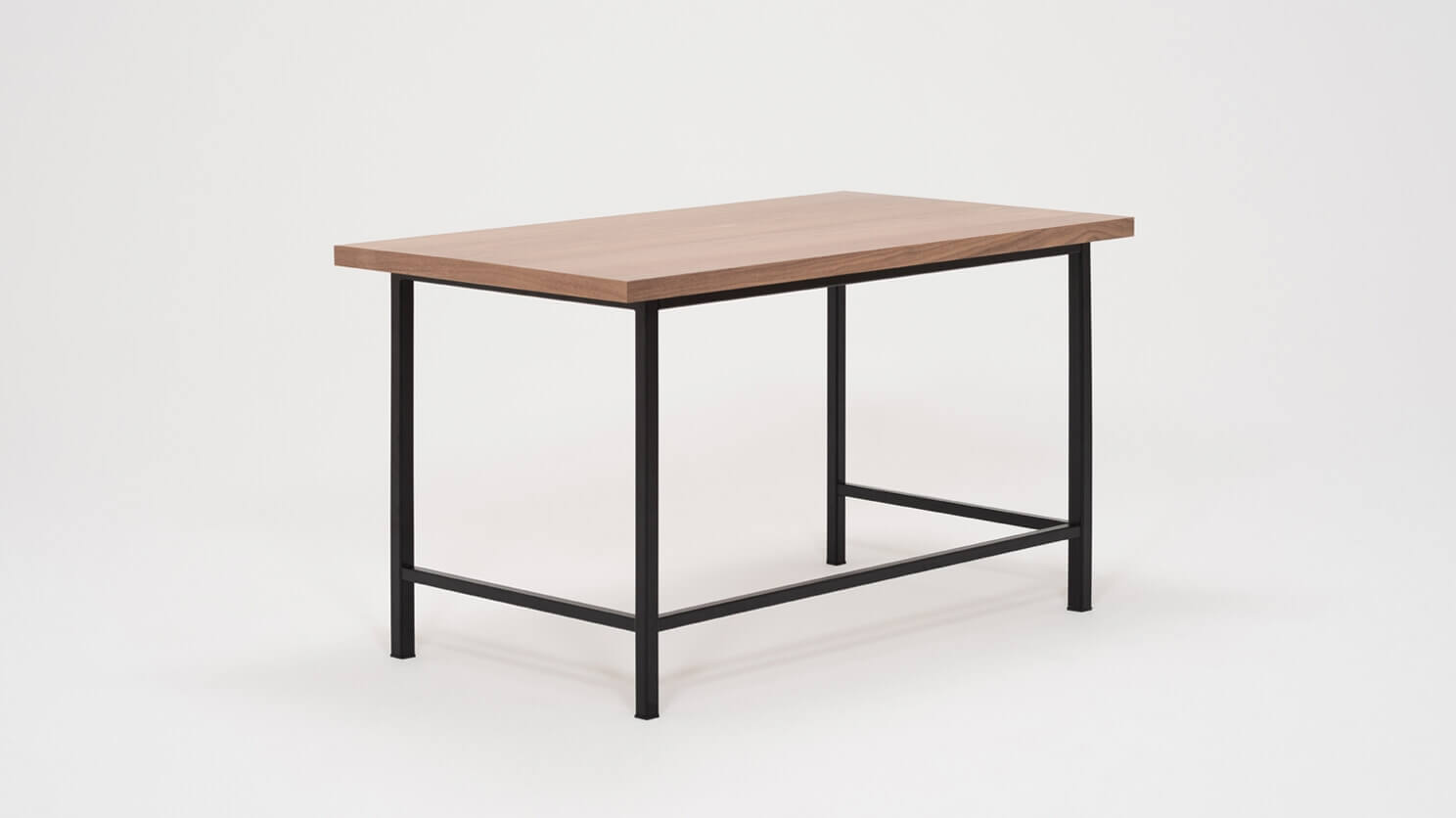 Angled view of the Kendall studio desk with walnut veneer top and black base