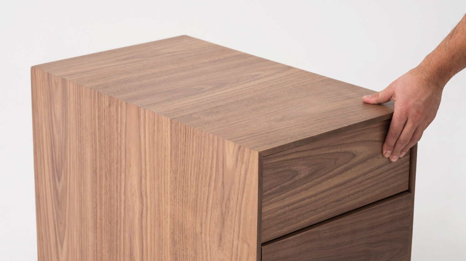 Walnut filing cabinet with hand on it top detail view