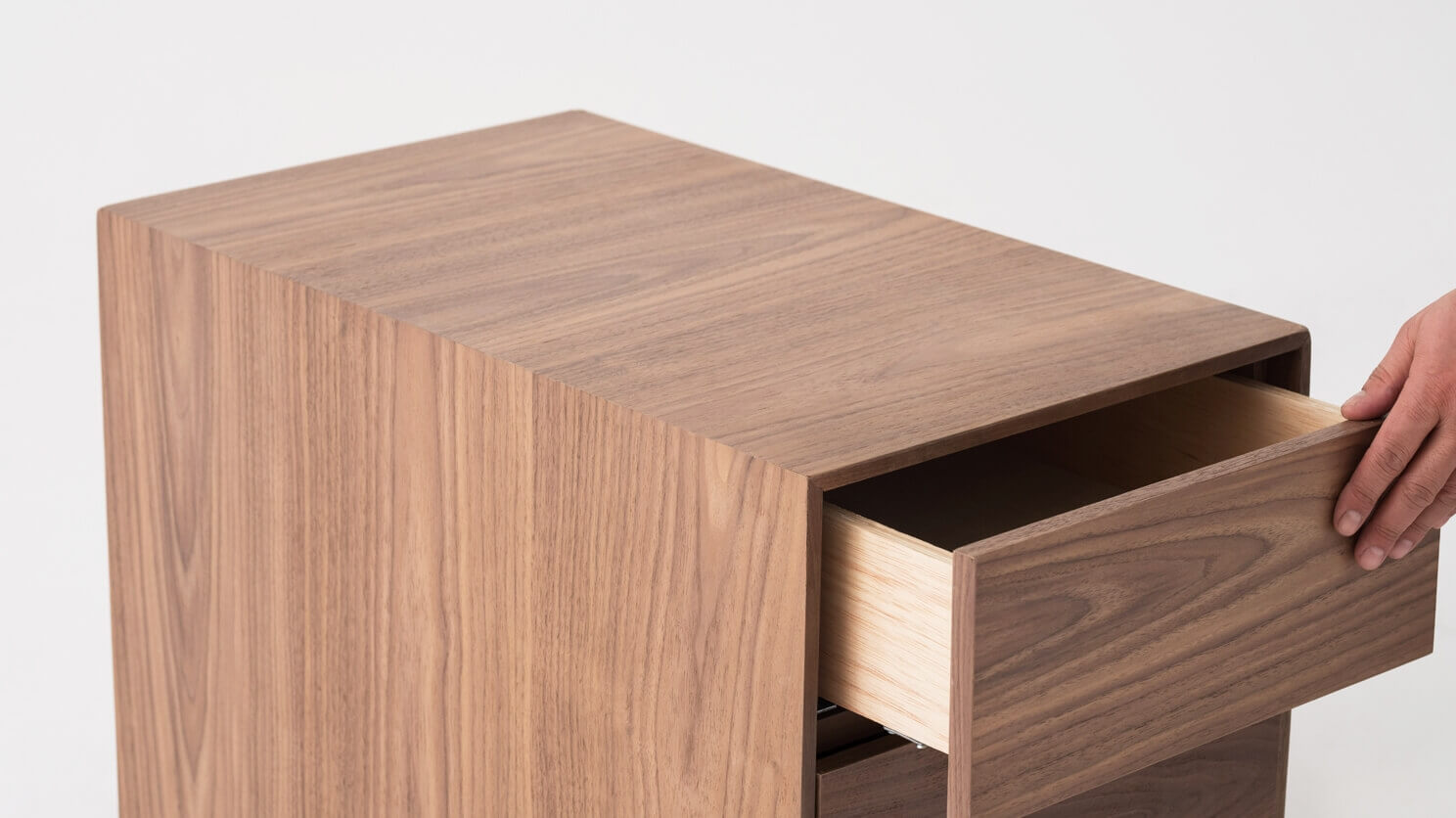 Top detail view of walnut filing cabinet with hand opening drawer