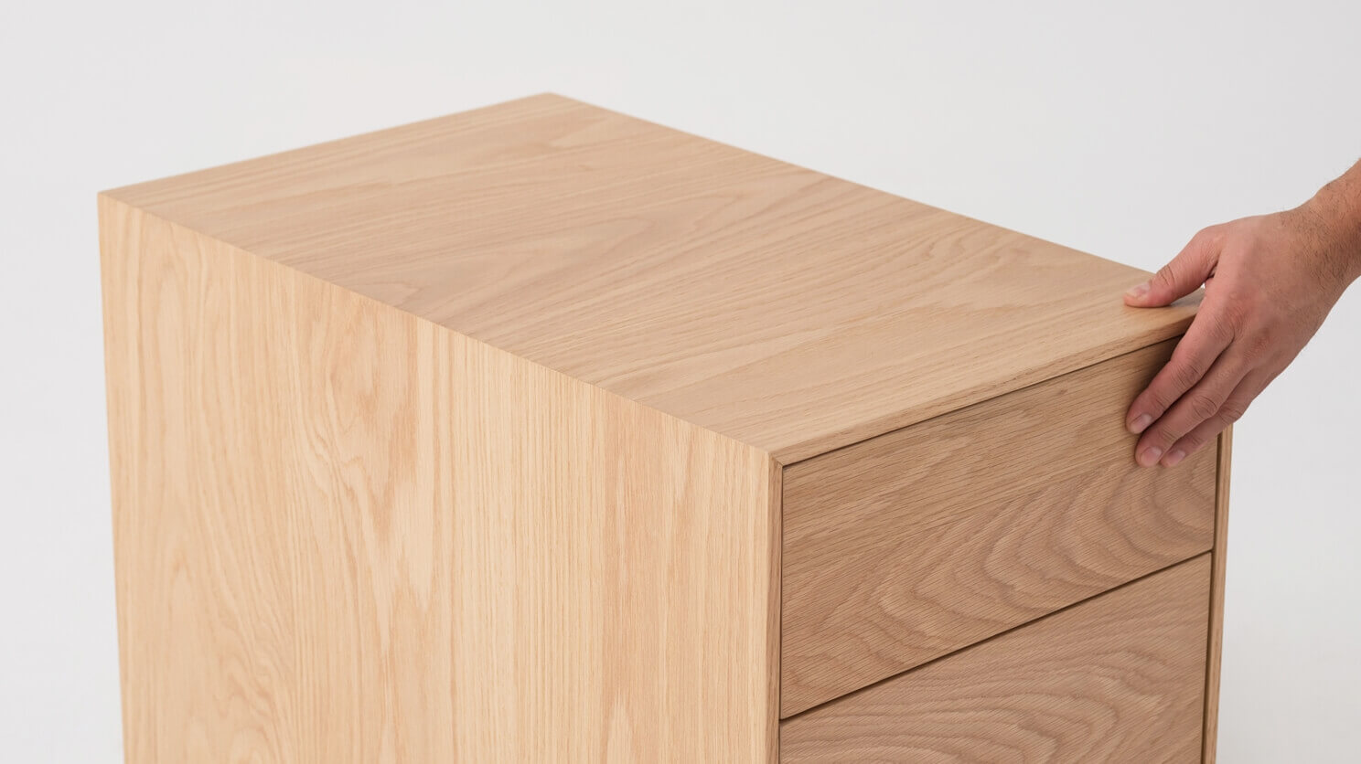 Top detail view of oak filing cabinet with hand on it