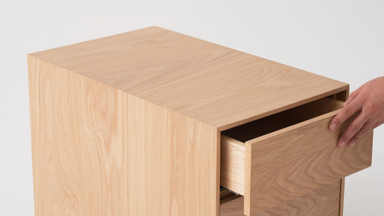 Top detail view of oak filing cabinet with hand opening drawer