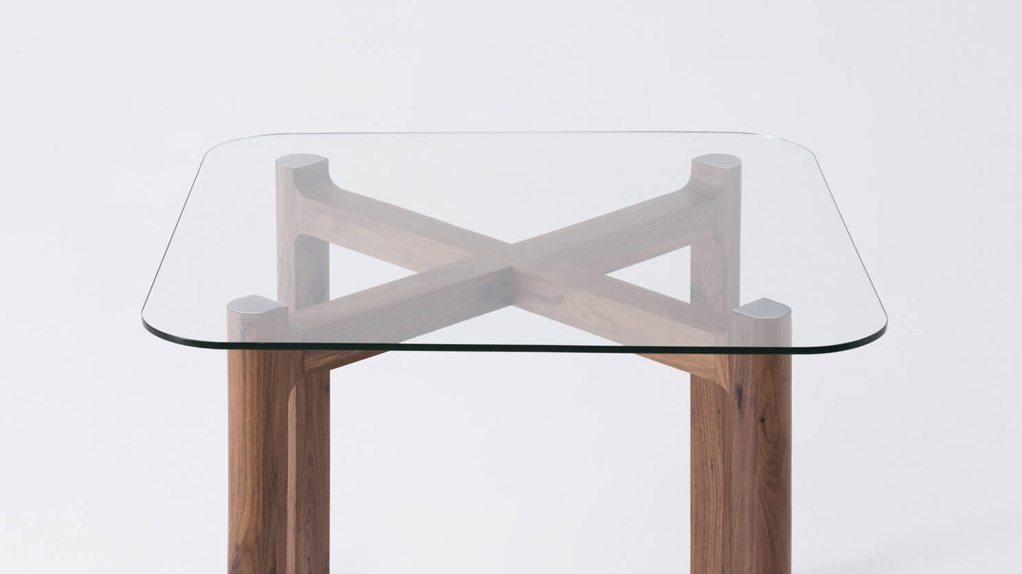 Detail view of the Place square contemporary dinette table with clear glass top and walnut legs