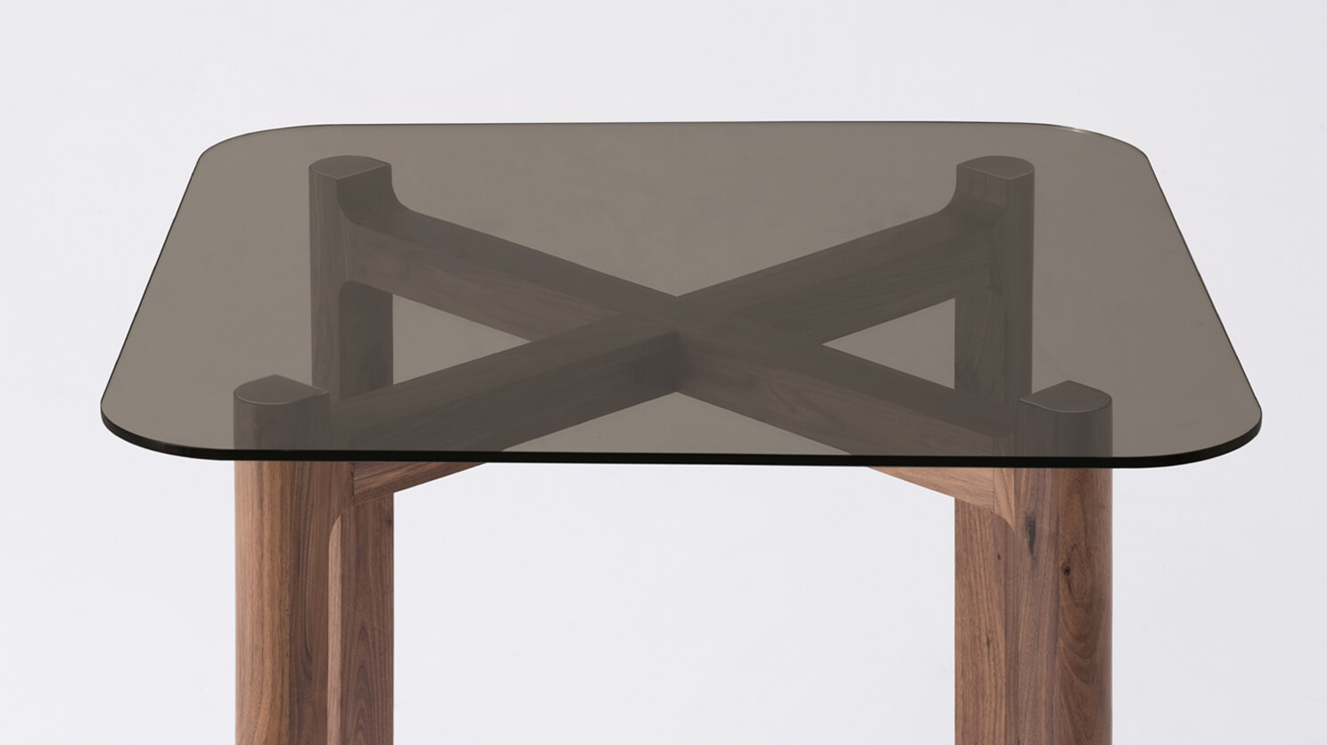 Detail view of the Place square contemporary dinette table with brown glass top and walnut legs