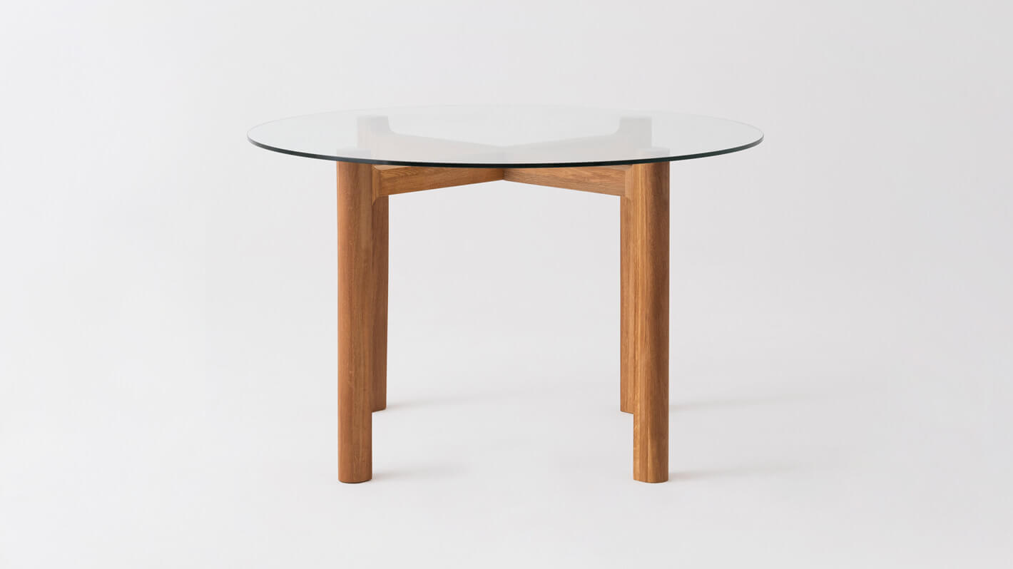 Front view of the Place round modern dinette table with clear glass top and oak legs