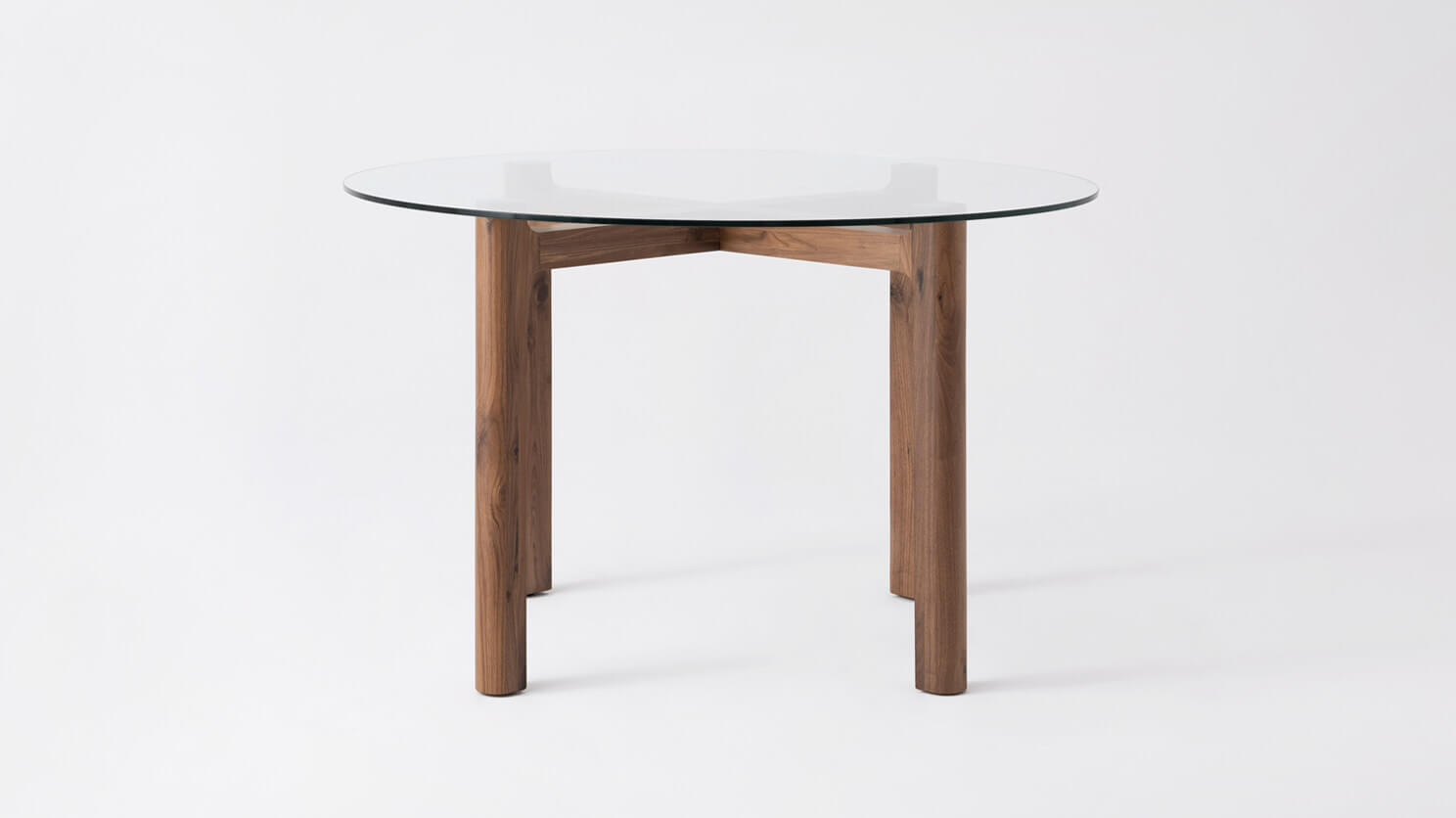 Front view of the Place round contemporary dinette table with clear glass top and walnut legs