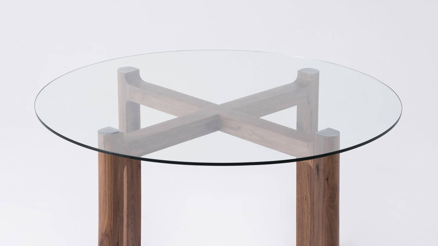 Detail view of the Place round contemporary dinette table with clear glass top and walnut legs