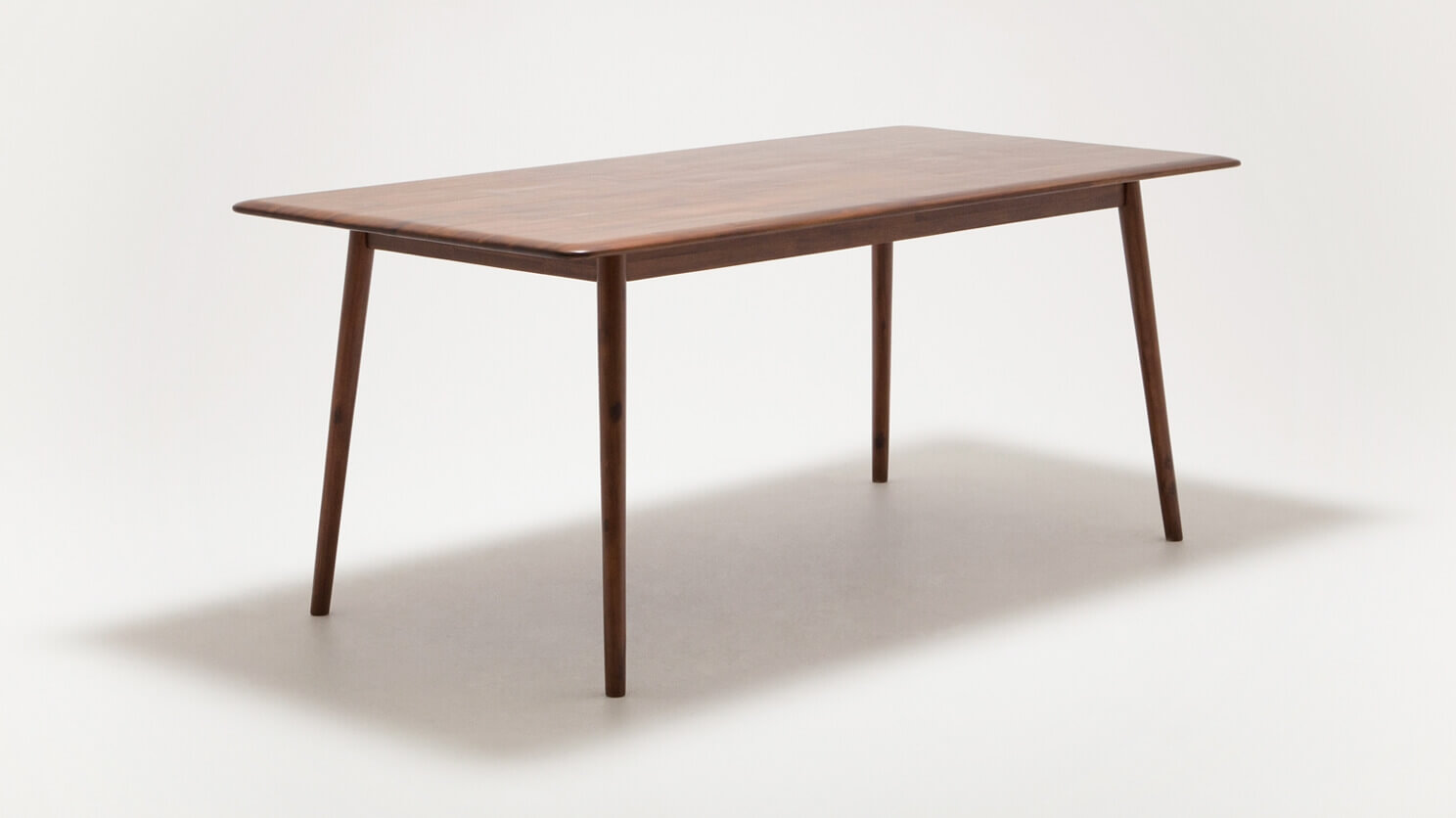 Angled view of the medium sized Kacia solid wood dining table in java