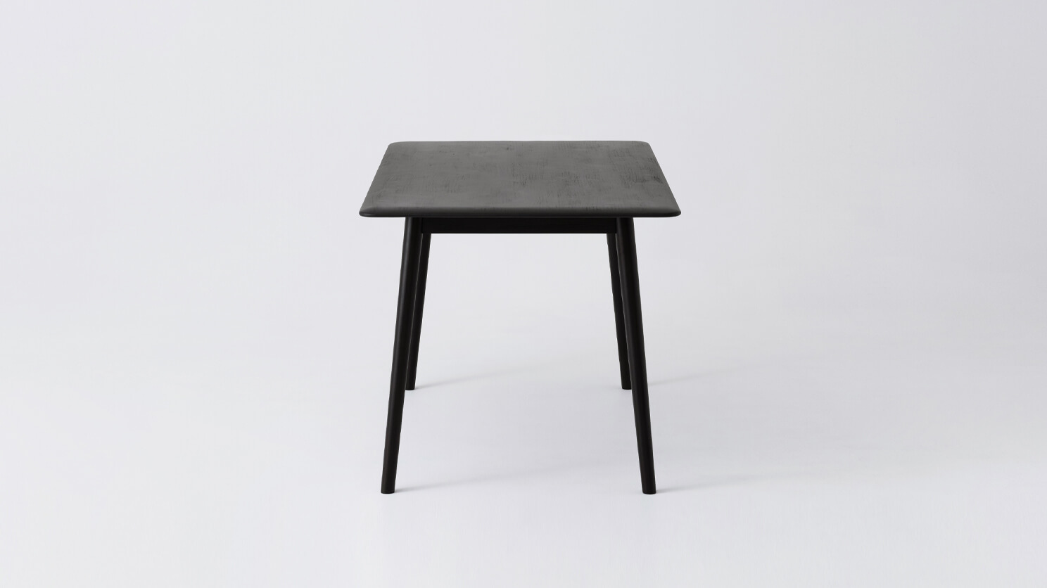 Side view of the small Kacia solid wood dining table in black