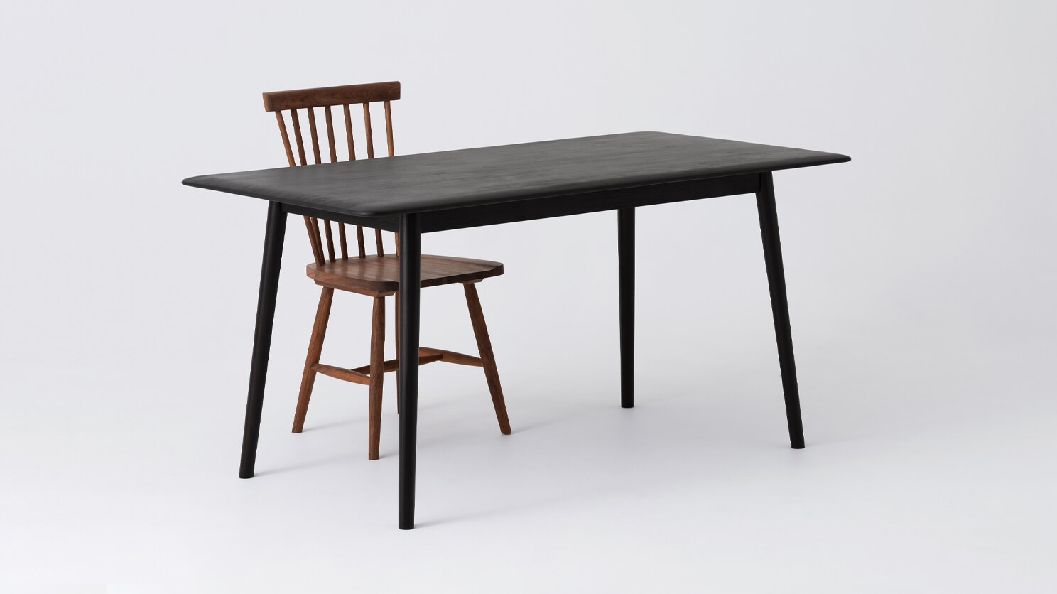 Angled view of the small Kacia solid wood dining table in black with red chair