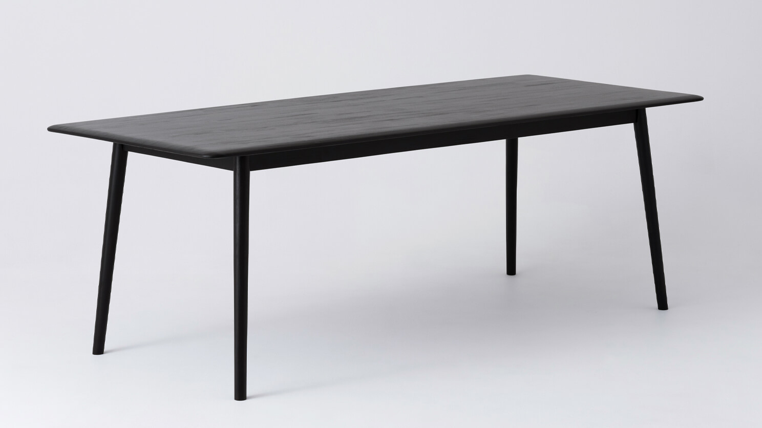 Angled view of the large Kacia solid wood dining table in black