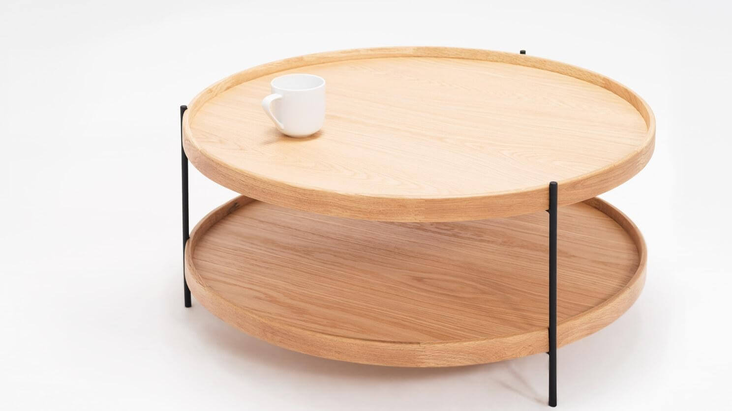 Detail view of the small Sage modern round coffee table in oak with coffee cup on it