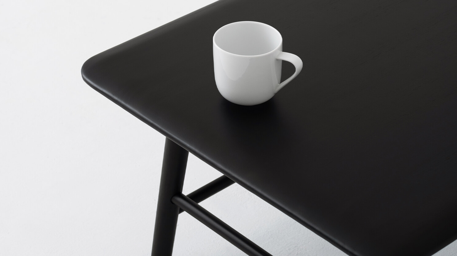 Detail view of the Kacia solid acacia wood coffee table in black with a coffee cup on it