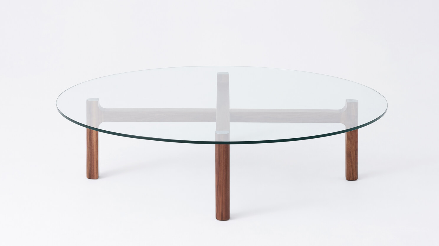 Side view of the Place small round coffee table with clear glass top and walnut legs