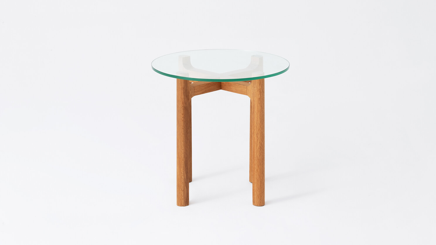 Front view of the Place round accent table with clear glass top and oak legs