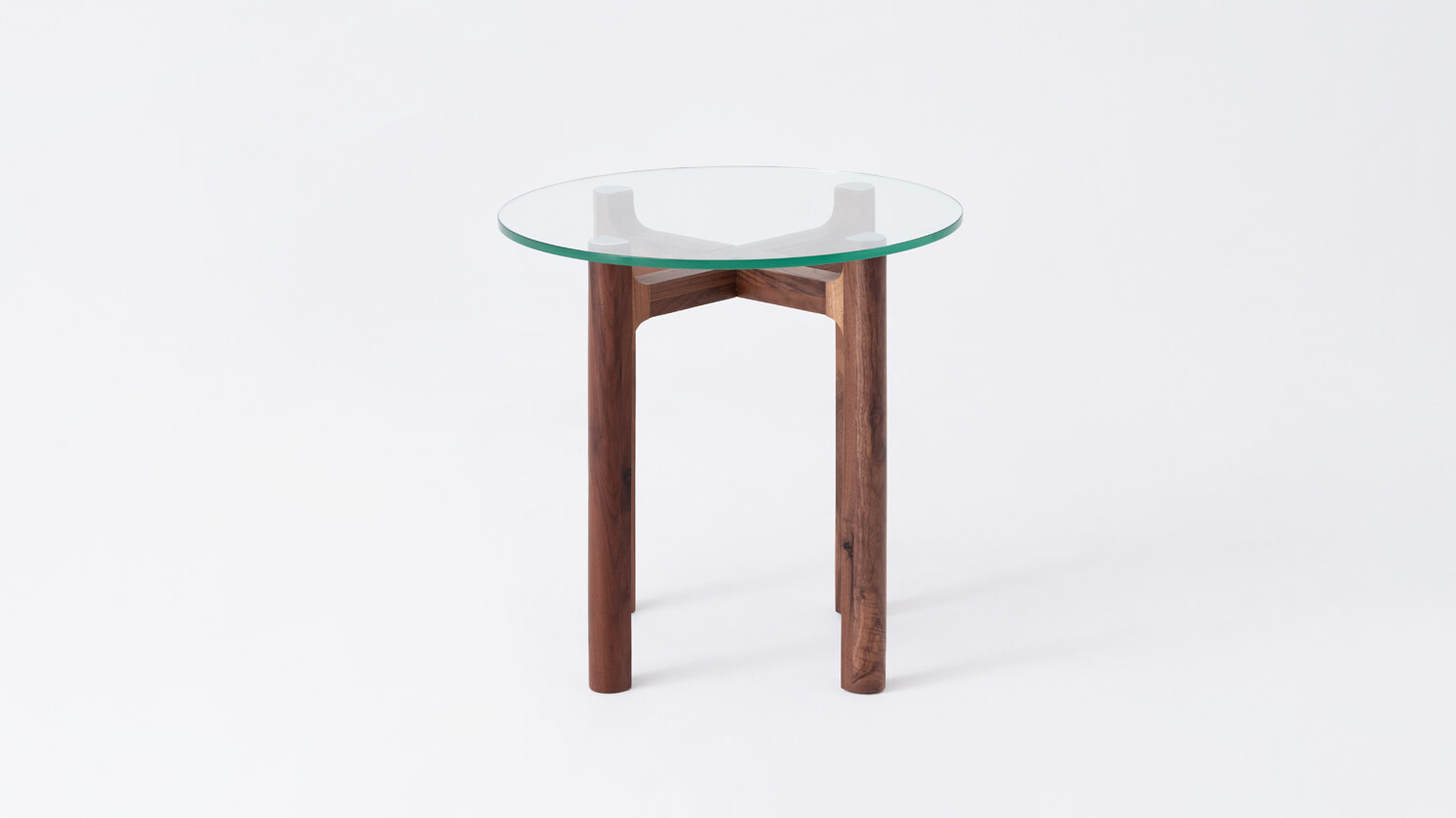 Front view of the Place round accent table with clear glass top and walnut legs