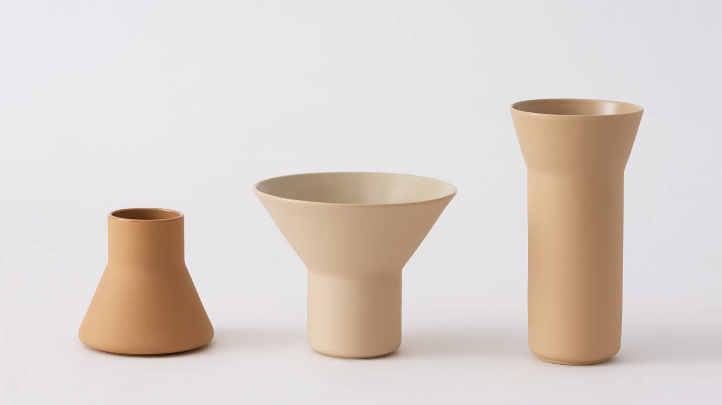 Small, medium, and large beige ceramic vases front view