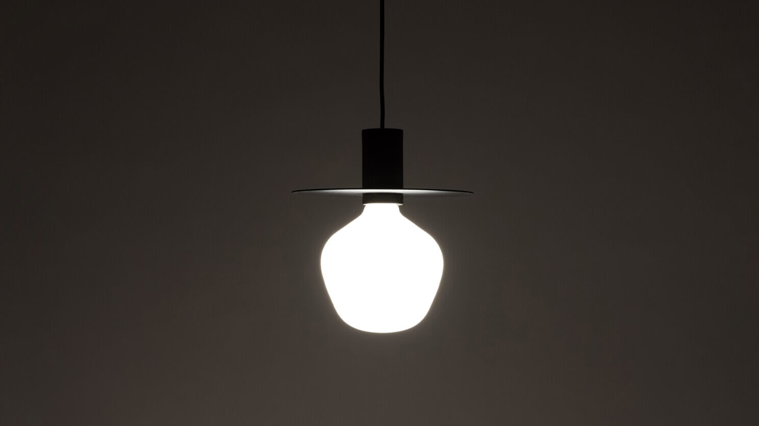 The Wellington Disc mid century Pendant lamp in black with light on