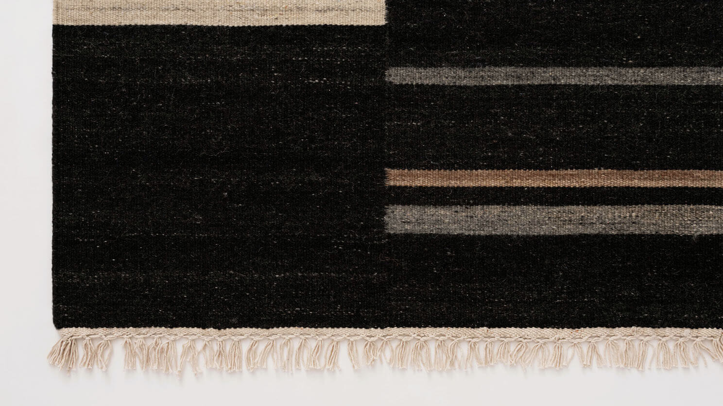 Black area rug with grey and brown stripes edge view