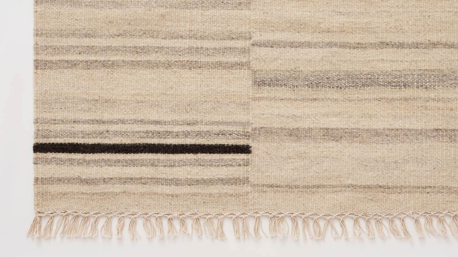 Detail edge view of ivory area rug with grey and black stripes