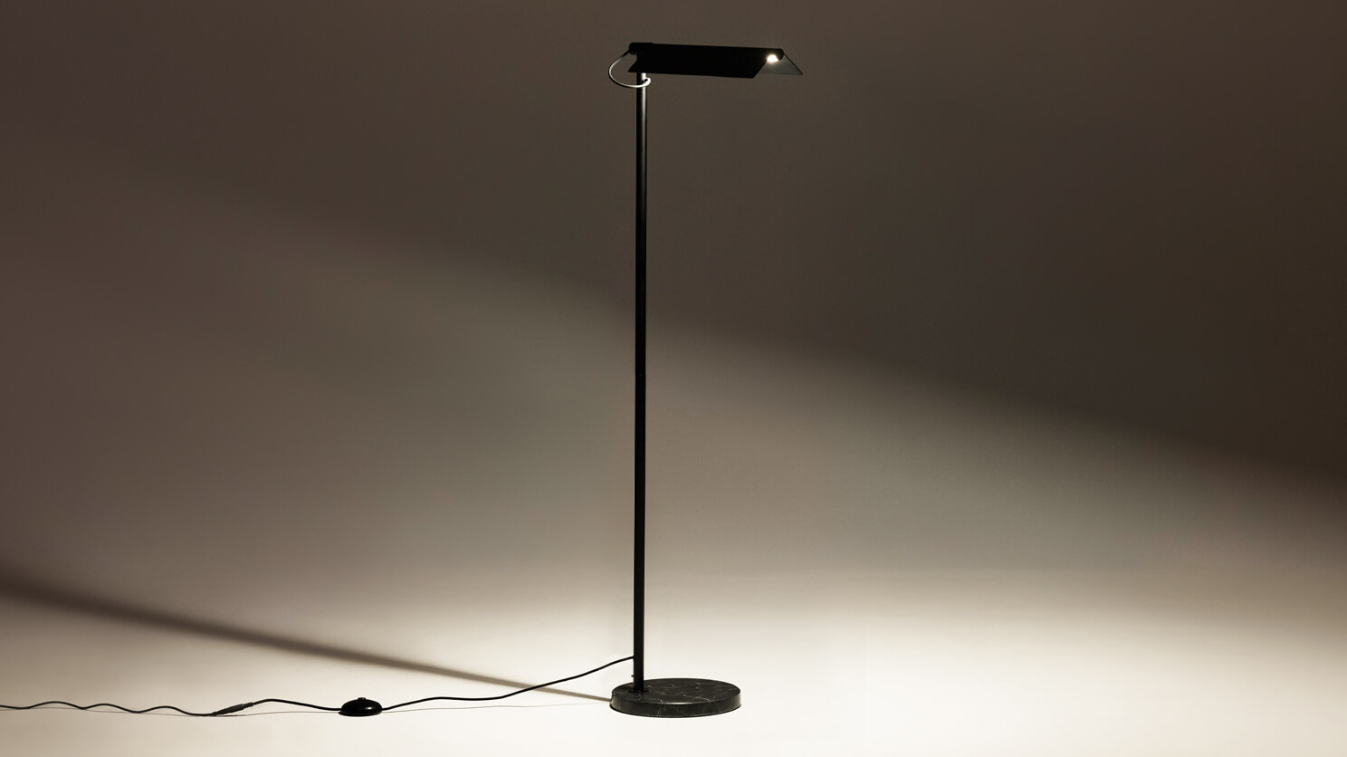 Angled view of the Oxford mid century floor lamp in black with light on