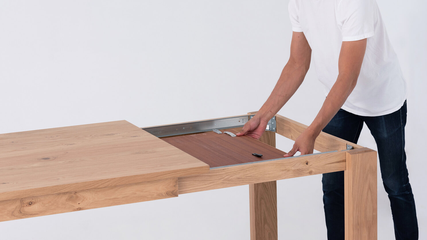 A man finds the leaf of the Bon solid wood dining table in oak