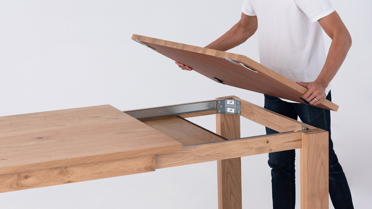 A man flips over the leaf of the Bon solid wood dining table in oak