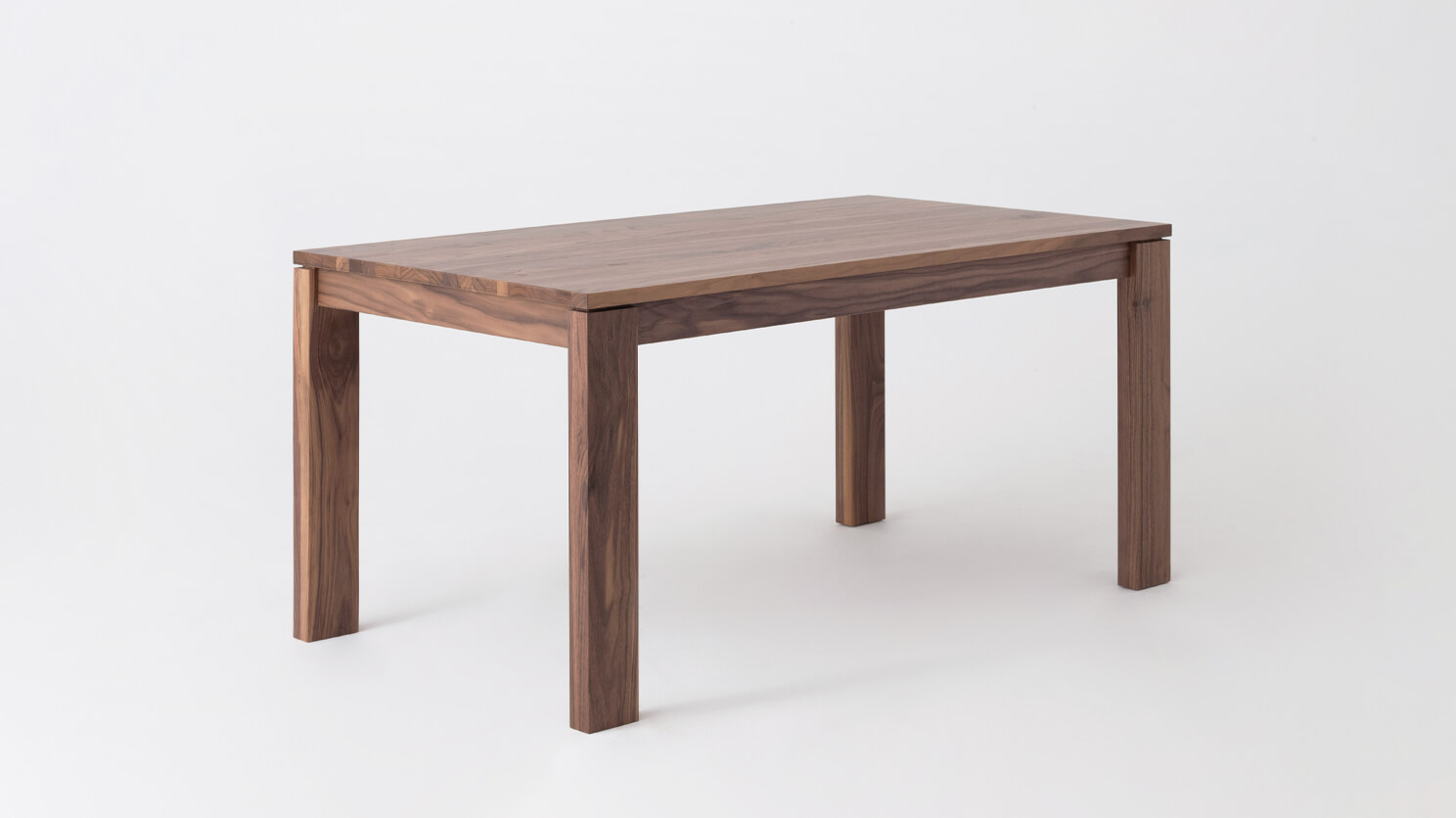 Angled view of the small Bon solid wood dining table in walnut