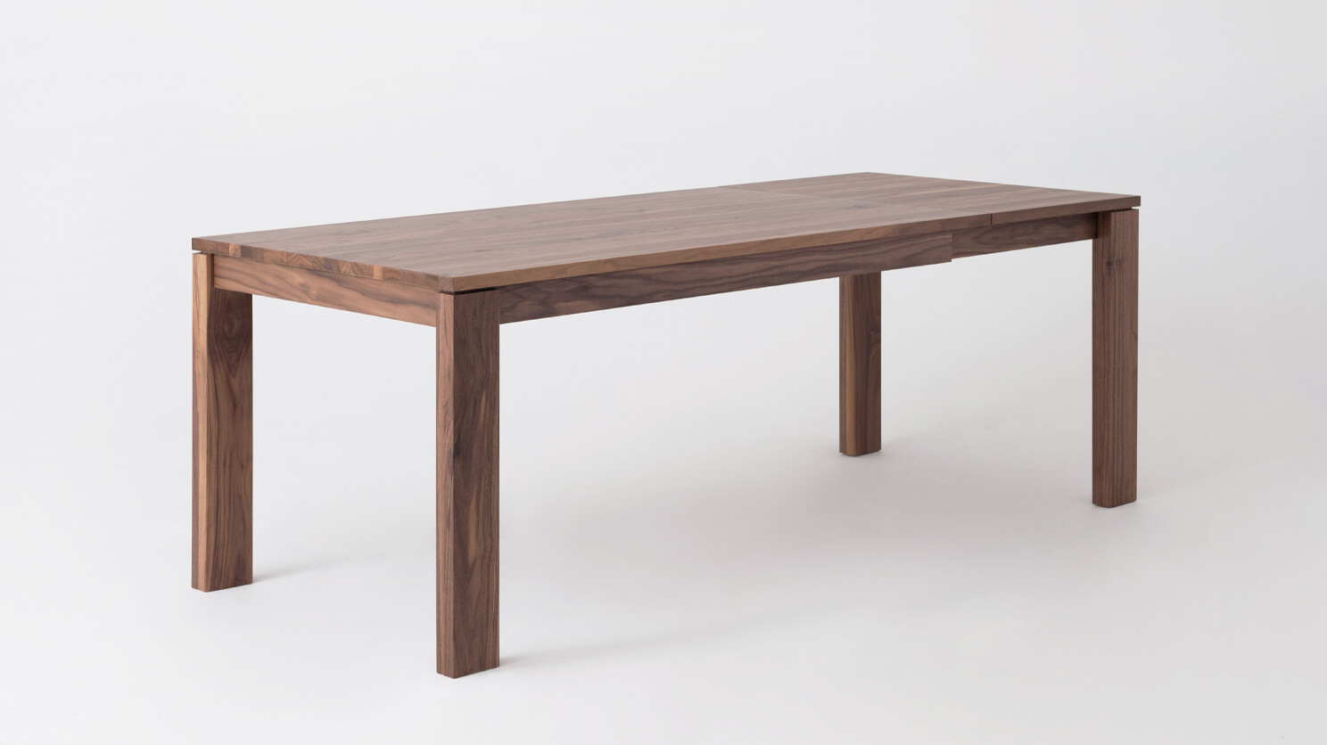 Angled view of the large Bon solid wood dining table in walnut