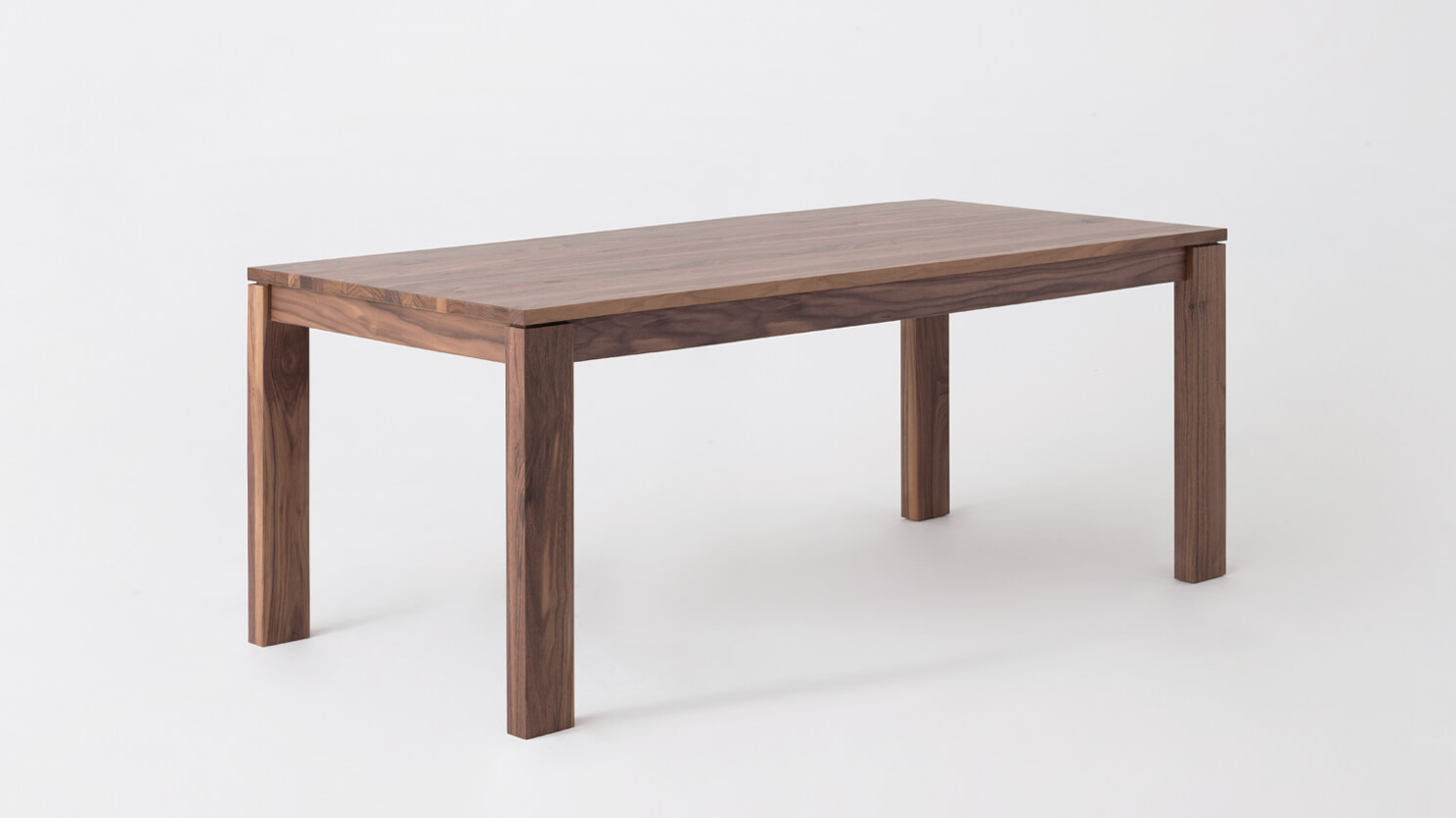 Angled view of the small Bon expanded solid wood dining table in walnut