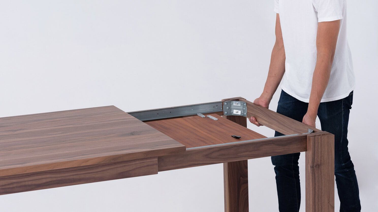 A man expands the Bon solid wood dining table in walnut all the way