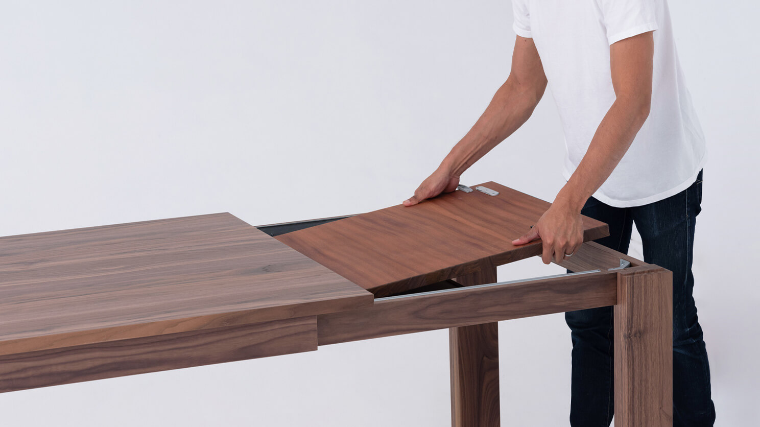 A man finds the leaf of the Bon solid wood dining table in walnut