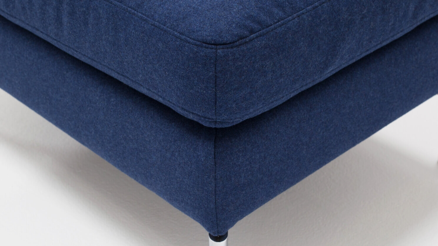 Corner view of the Eve mid century ottoman in blue fabric