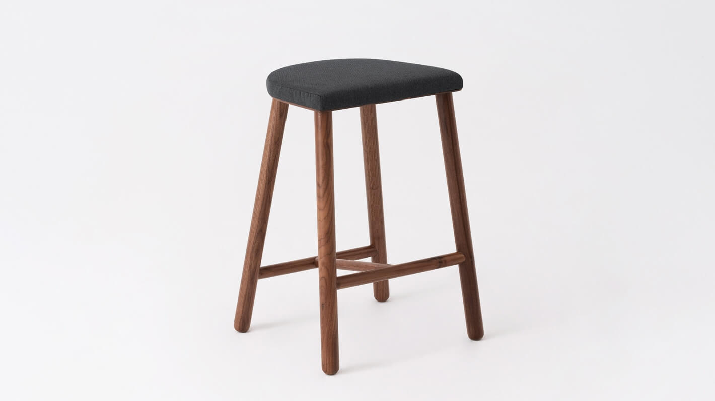 Angled view of the Lima custom counter height stool with black seat and walnut base