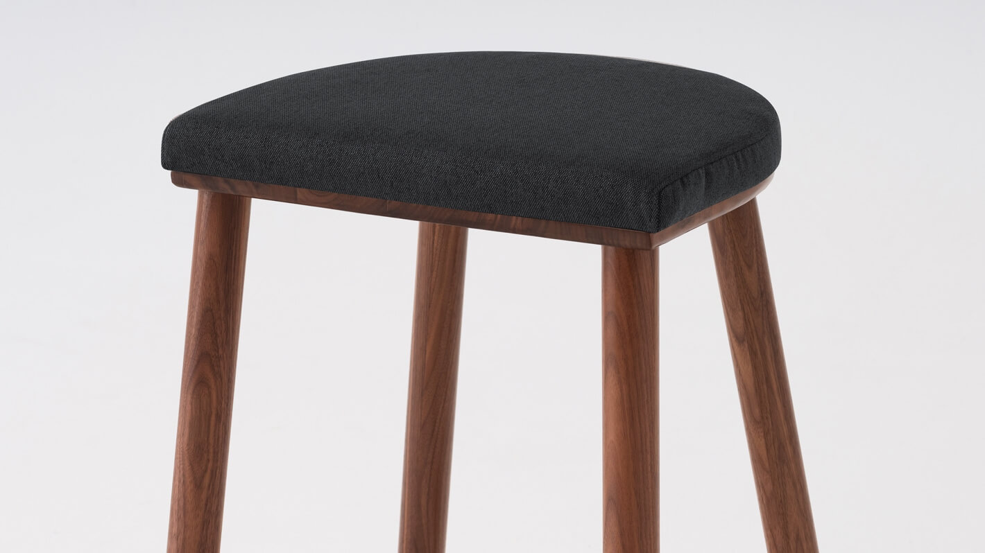 Detail view of the Lima custom counter stool with black seat and walnut base