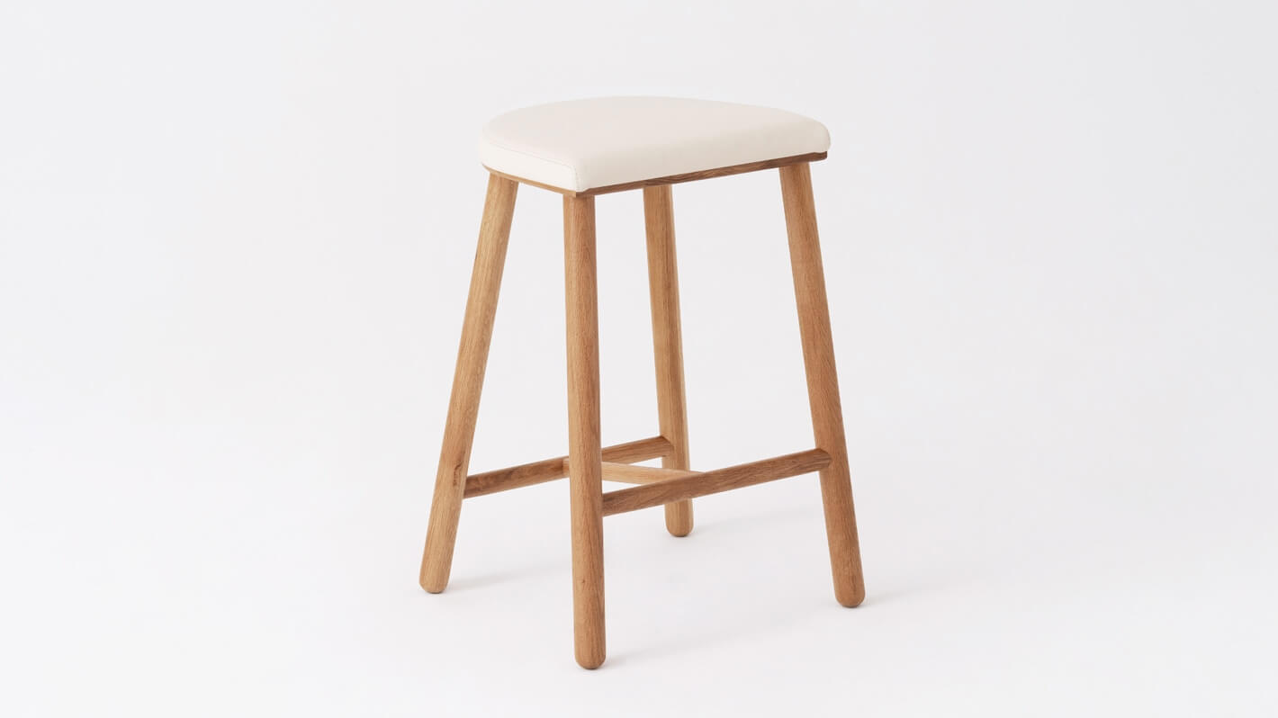 Angled view of the Lima custom counter stool with white leather seat and oak base