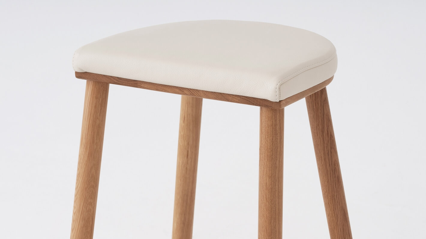 Detail view of the Lima custom counter stool with white leather seat and oak base