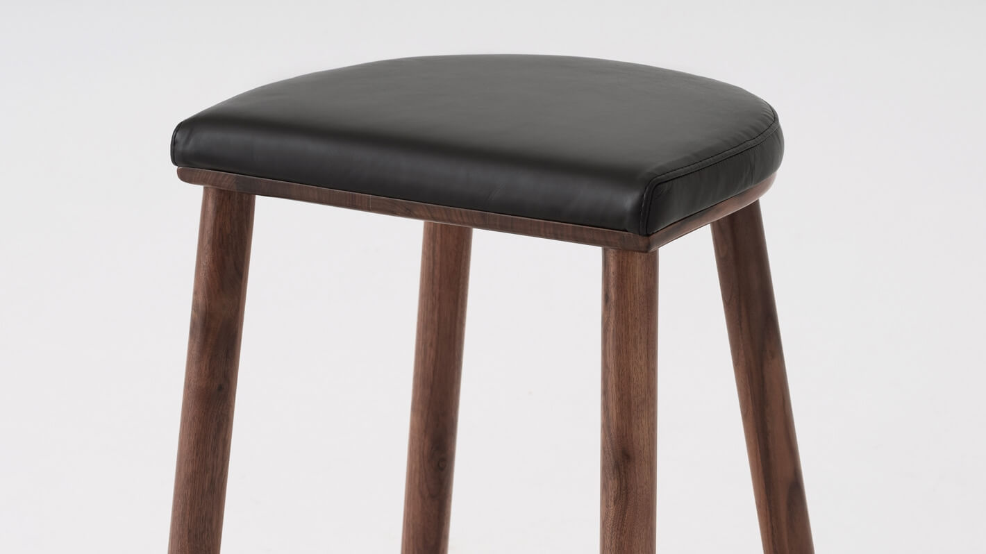 Detail view of the Lima custom counter stool with black leather seat and walnut base