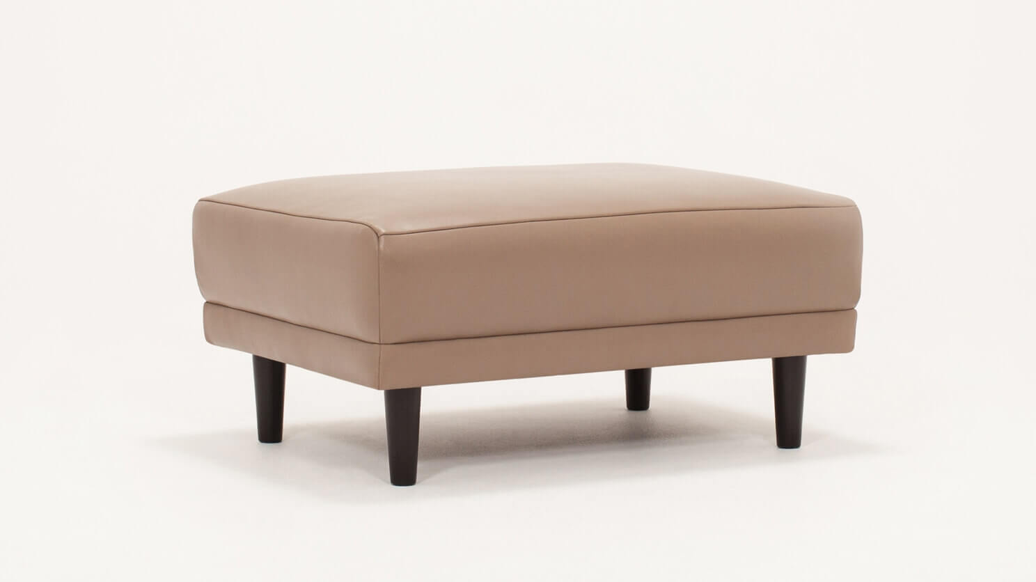 Angled view of the Remi modern ottoman in beige leather