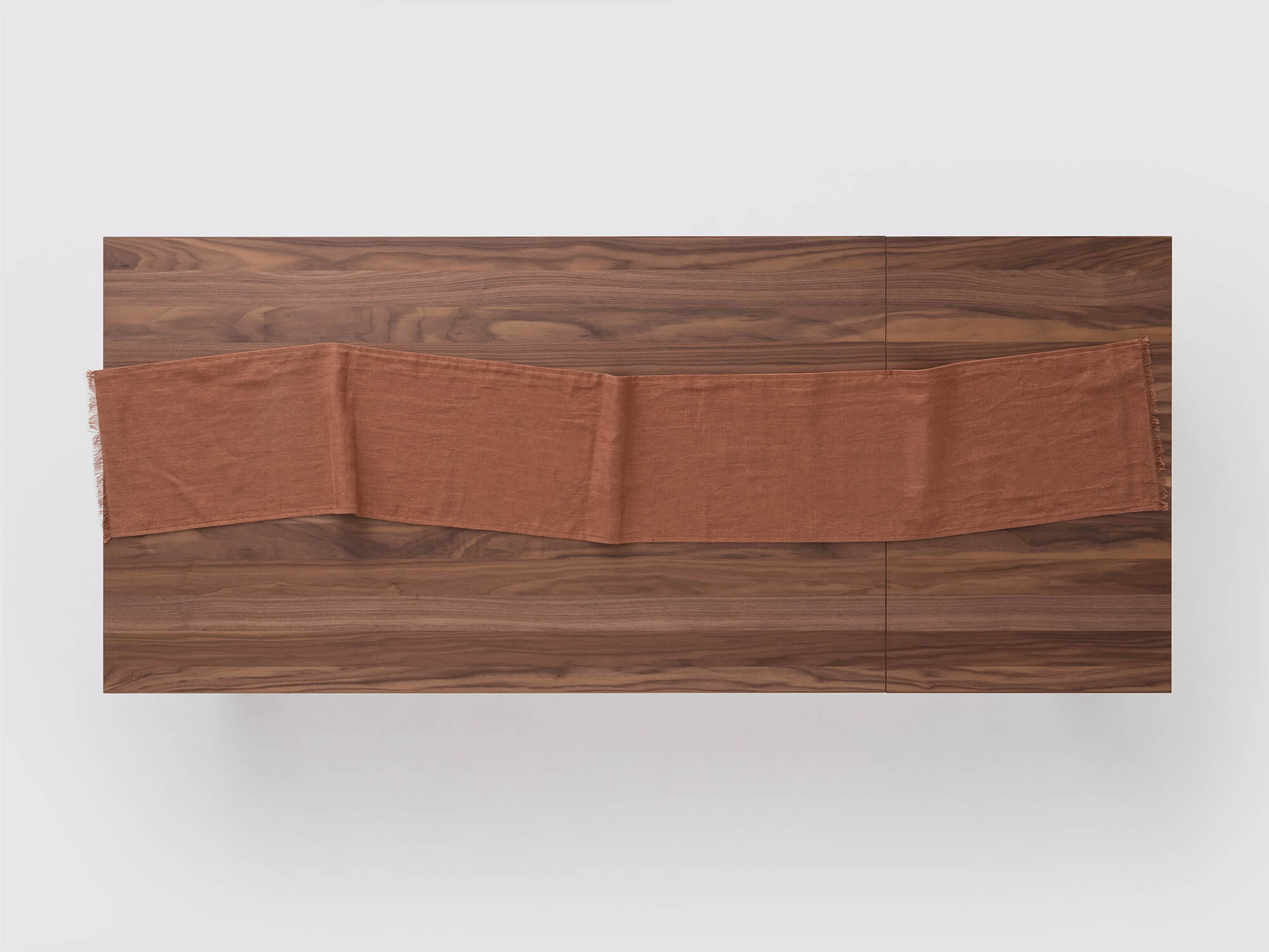 Overhead view of the Faye burnt red table runner on a table