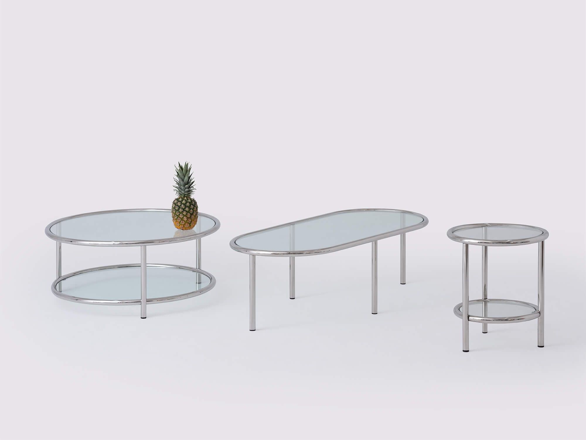 Front view of stainless steel and glass end table, round coffee table, and oval coffee table