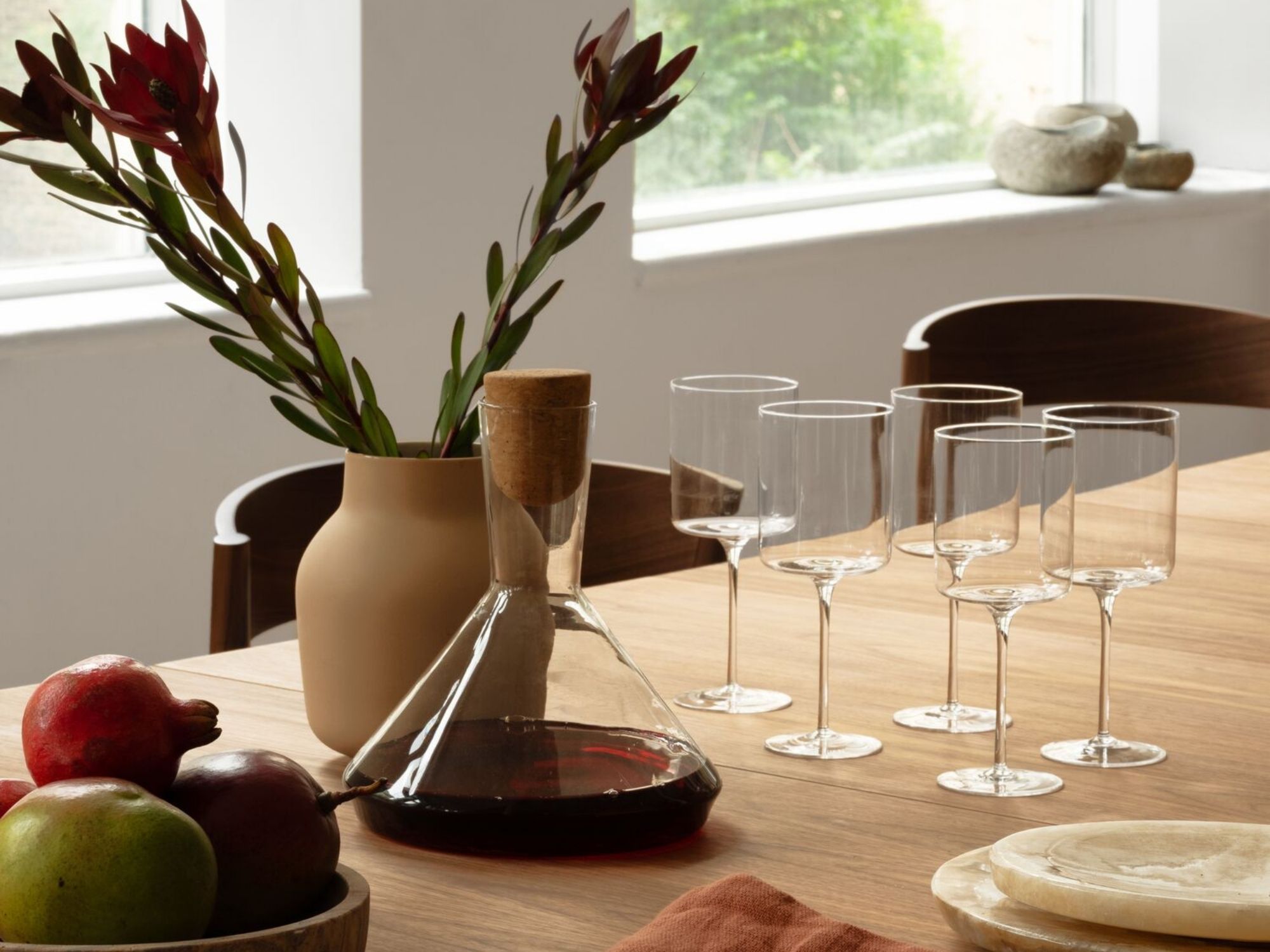 Red wine decanter and wine glasses on dining table set for dinner