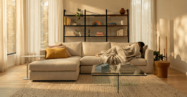 Un grand sofa vert, une table en noyer et deux chaises sont présentés dans un salon moderne. Lien vers la catégorie canapes modulaires