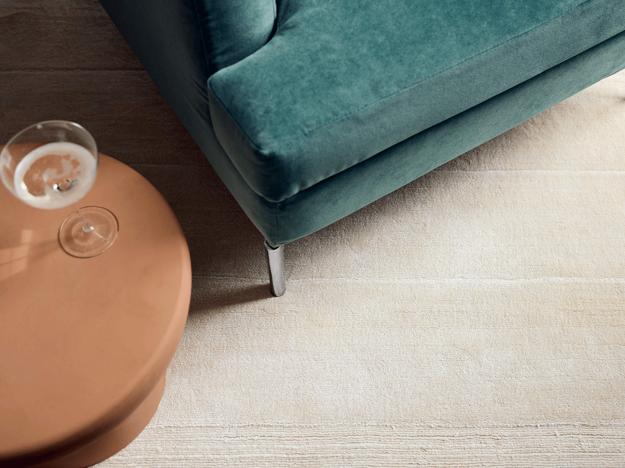 Ivory area rug with green armchair and terracotta stool on it