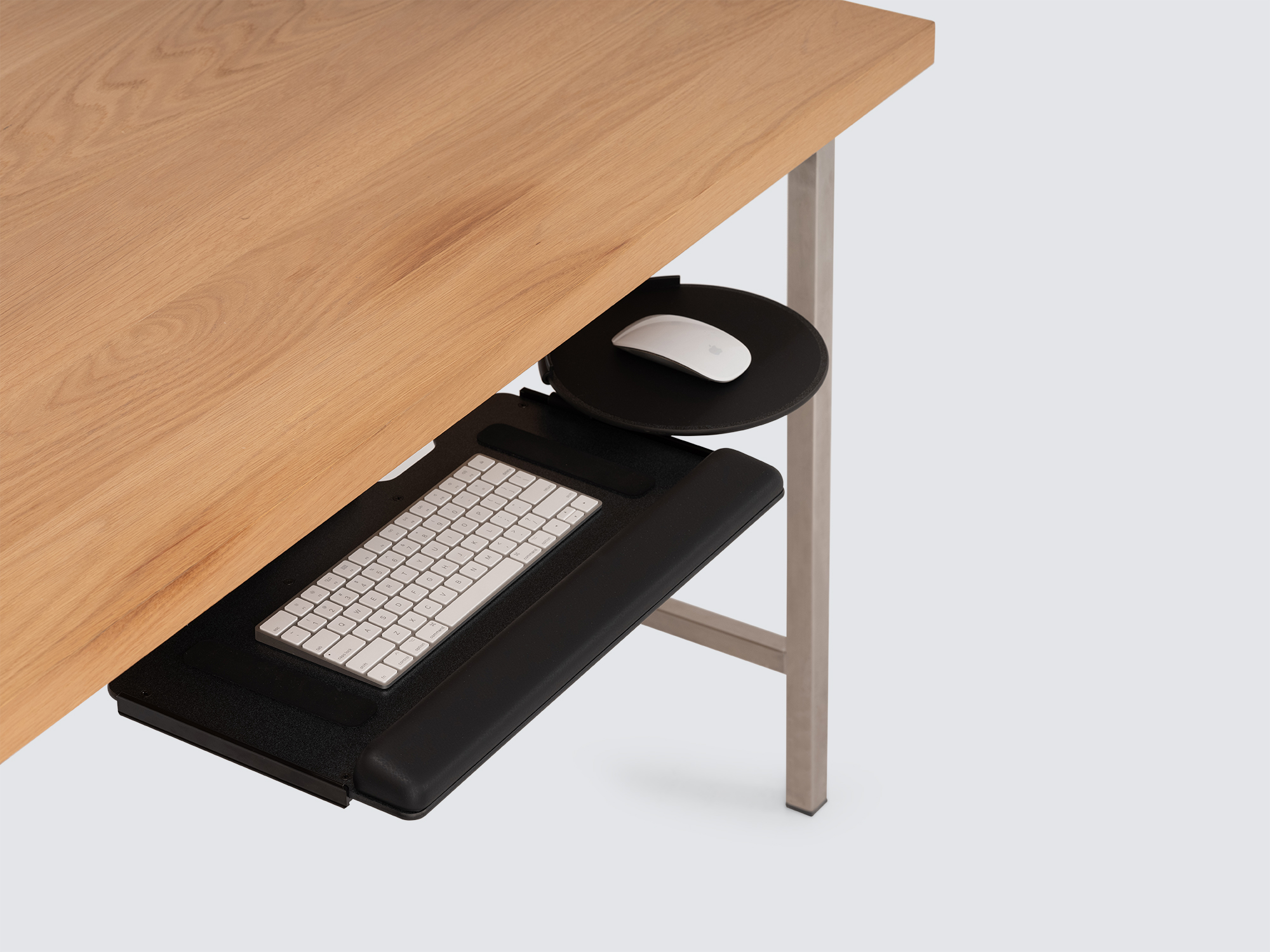 The Humanscale Keyboard Tray in black halfway pulled out from an oak desk