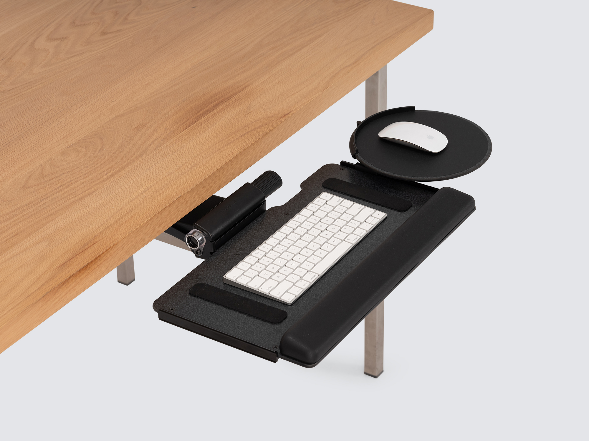 The Humanscale Keyboard Tray in black partially pulled out from an oak desk