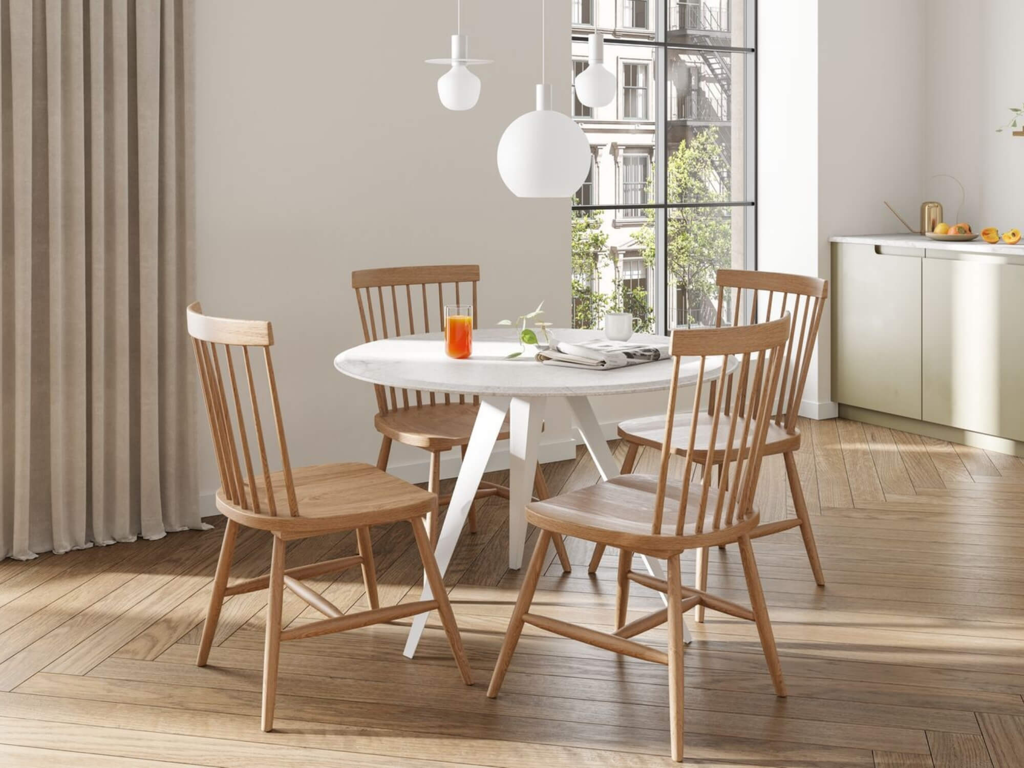 Three white pendant lights over white dinette table with oak chairs